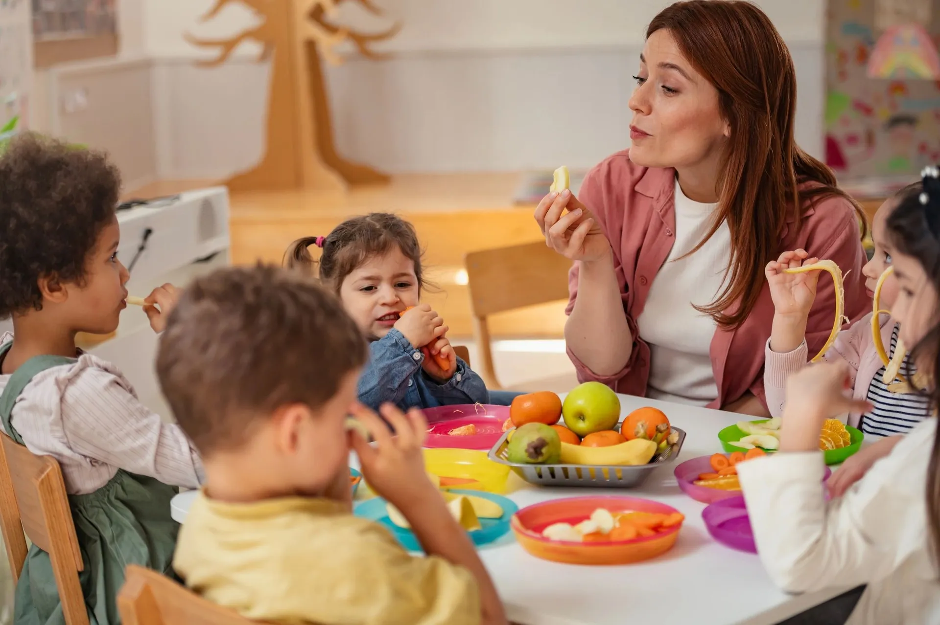 An educator sharing a healthy snack with preschool children